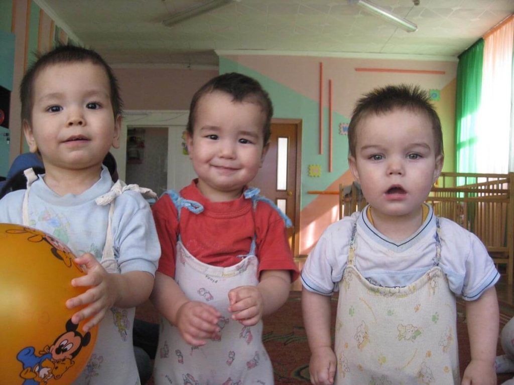 Three boys in an institution standing in a row and smiling