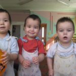 Three boys in an institution standing in a row and smiling