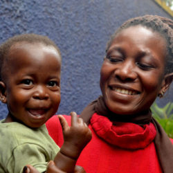 Smiling caregiver holding a young boy who is also smiling