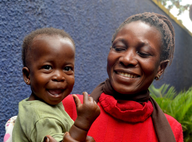 Smiling caregiver holding a young boy who is also smiling