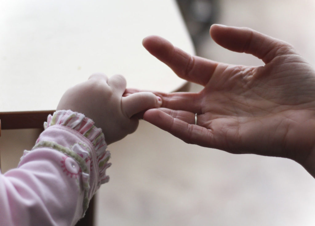 An adult holding hands with a young child