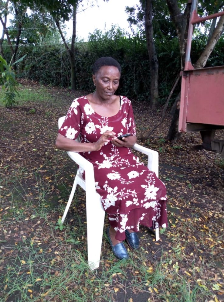 Matron Matron, a SPOON trainee, accessing SPOON's curriculum online using a smartphone while sitting outside on a chair