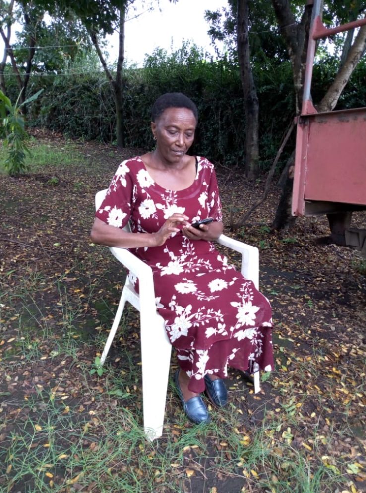 Matron, a SPOON trainee, accessing SPOON's curriculum online using a smartphone while sitting outside on a chair