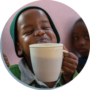 Boy in Tanzania smiling and holding a mug