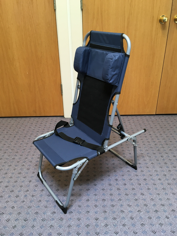 Prototype of the SPOON Chair from the front: a navy blue, aluminum folding chair with padding on the sides and a black belt