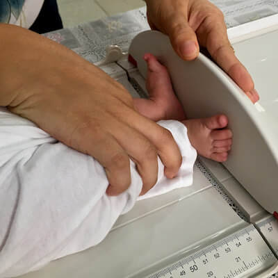 An infant's small feet on a length board, getting measured.