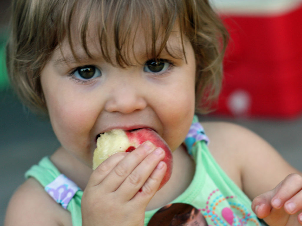 Young girl eating a peach