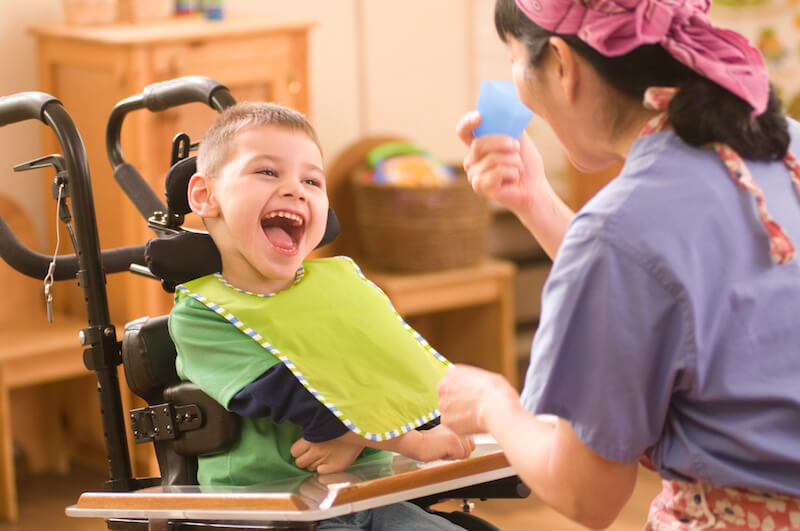 Child in wheelchair smiling with cup