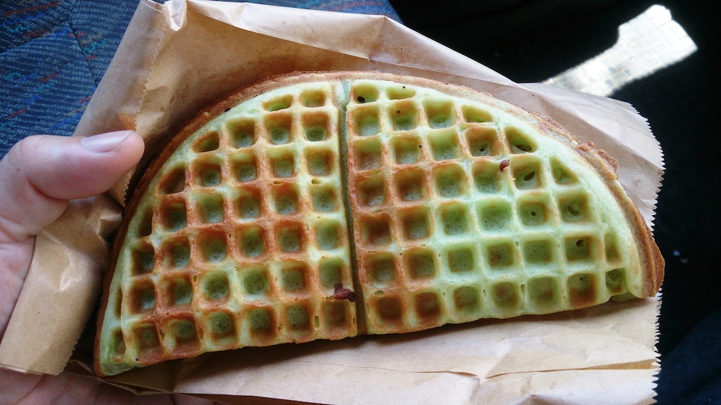 Photo of a someone holding an Egg waffle in a paper bag